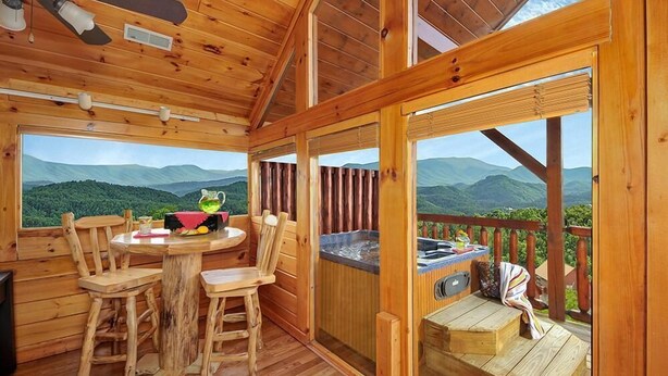 A wooden cabin with a dining area, a hot tub, and a deck with a mountain view. - Mountain Splendor: Best Mountain View in Starr Crest Resort - Brand New Hot Tub (Sevierville)