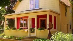 Een huis met twee verdiepingen, een veranda, een voordeur en een kleine tuin.