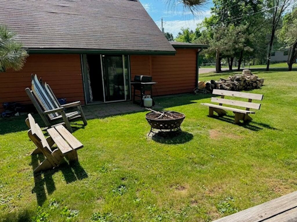 A backyard with a wooden deck, a fire pit, and a bench.