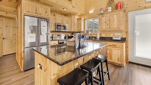 A wooden cabin-style kitchen with a central island, stainless steel appliances, and wooden cabinets.
