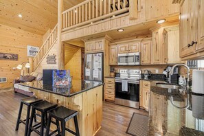 L’intérieur d’un chalet en bois comprend une cuisine, un coin bar et un escalier.