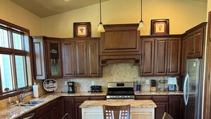 Una cocina amplia con armarios de madera oscura, una isla central, un refrigerador de acero inoxidable y una mesa de comedor con sillas.