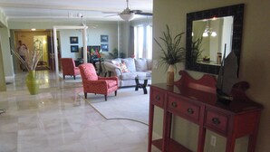 A spacious living room with a large mirror, a red armchair, a white sofa, and a coffee table. -  Beautiful Oceanview Margate. Book now for June and July (Myrtle Beach)