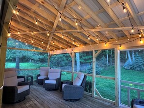 A covered outdoor seating area with wicker chairs and string lights. - Lake Michigan Waterfront Retreat - Traverse City, MI (Traverse City)