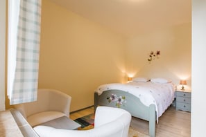 A bedroom with a bed, two chairs, a nightstand, and a wall-mounted lamp. - Reka Hisa  River Side Chalet (Bled)