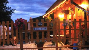 A wooden fence with a sign reading "REKA HISA" and a wooden building with hanging flower baskets.