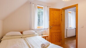 Een slaapkamer met een bed, twee ramen, een houten deur en een radiator.