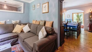 Een woonkamer met een bruine modulaire bank, een eettafel voor vier personen en een grote spiegel aan de muur.