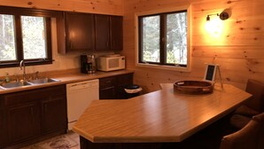 Une cuisine de style rustique, avec des murs en bois, un îlot central, un four à micro-ondes et une machine à café.