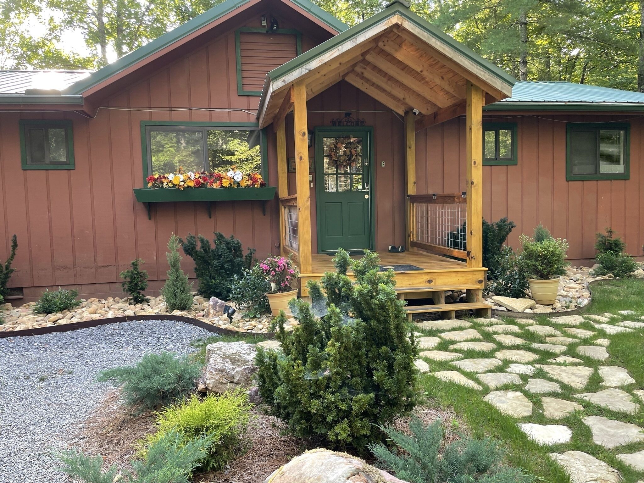A wooden cabin with a porch, a green door, and a flower box.