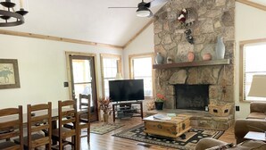 Amplia sala de estar con chimenea de piedra, muebles de madera y televisor.