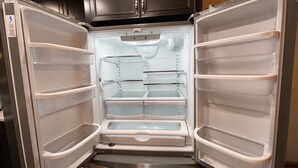 Un refrigerador abierto con varias estantes y cajones, un dispensador de agua y un compartimento congelador.