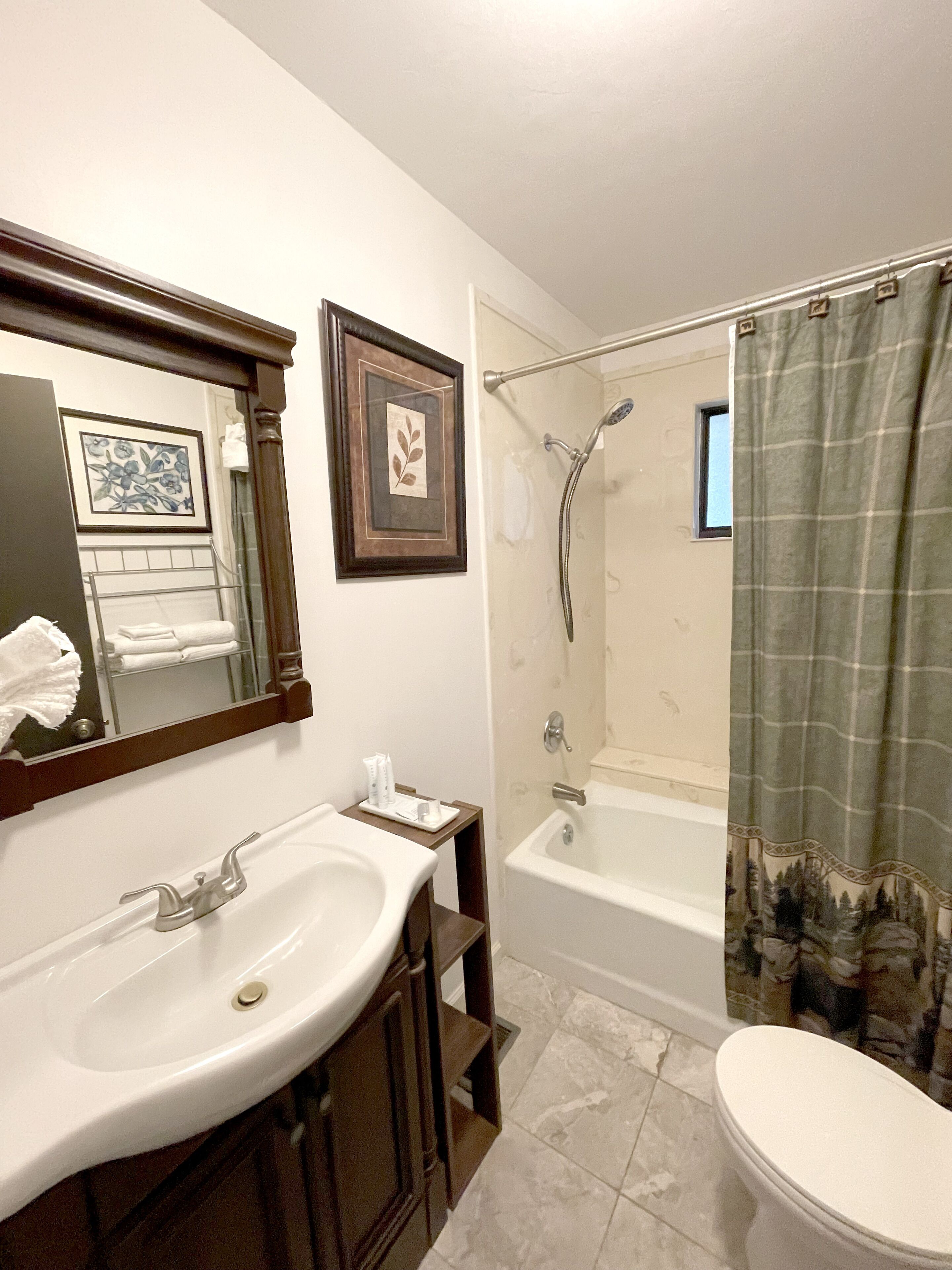 A bathroom with a double sink, a bathtub, a shower, and a toilet.