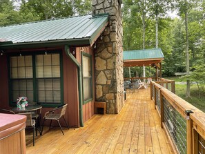 Une terrasse en bois avec un muret en pierre et un espace salon abrité.