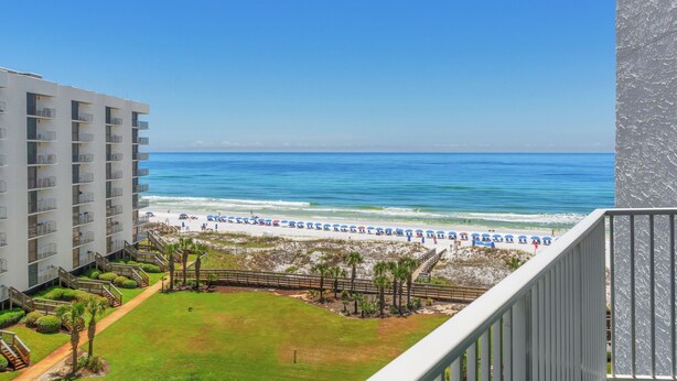 A view of a beach with umbrellas and a building with multiple floors and balconies. - Mainsail-On beach-Renovated 2BR/BA with 1 beach umbrella/chairs setup to Oct 31 (Destin)
