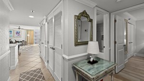 A hallway with white walls, a glass table with a lamp, and a mirror. - Mainsail-On beach-Renovated 2BR/BA with 1 beach umbrella/chairs setup to Oct 31 (Destin)