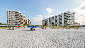 A beachfront hotel with multiple-story buildings, sandy beach, and umbrellas. - Mainsail-On beach-Renovated 2BR/BA with 1 beach umbrella/chairs setup to Oct 31 (Destin)