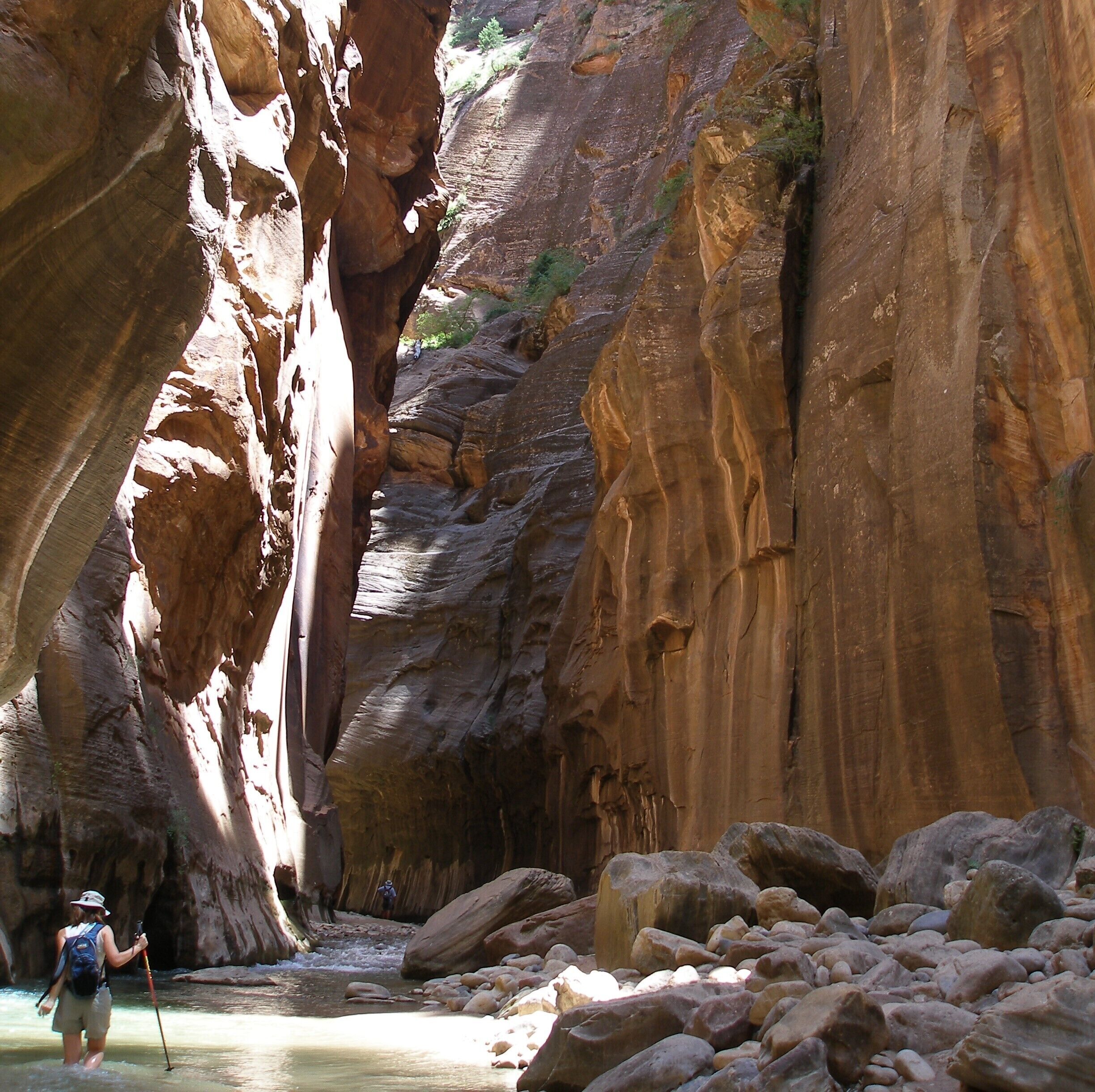A narrow canyon with large boulders and a river.