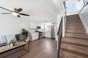 Una cocina moderna con armarios blancos, un microondas y un refrigerador de acero inoxidable.