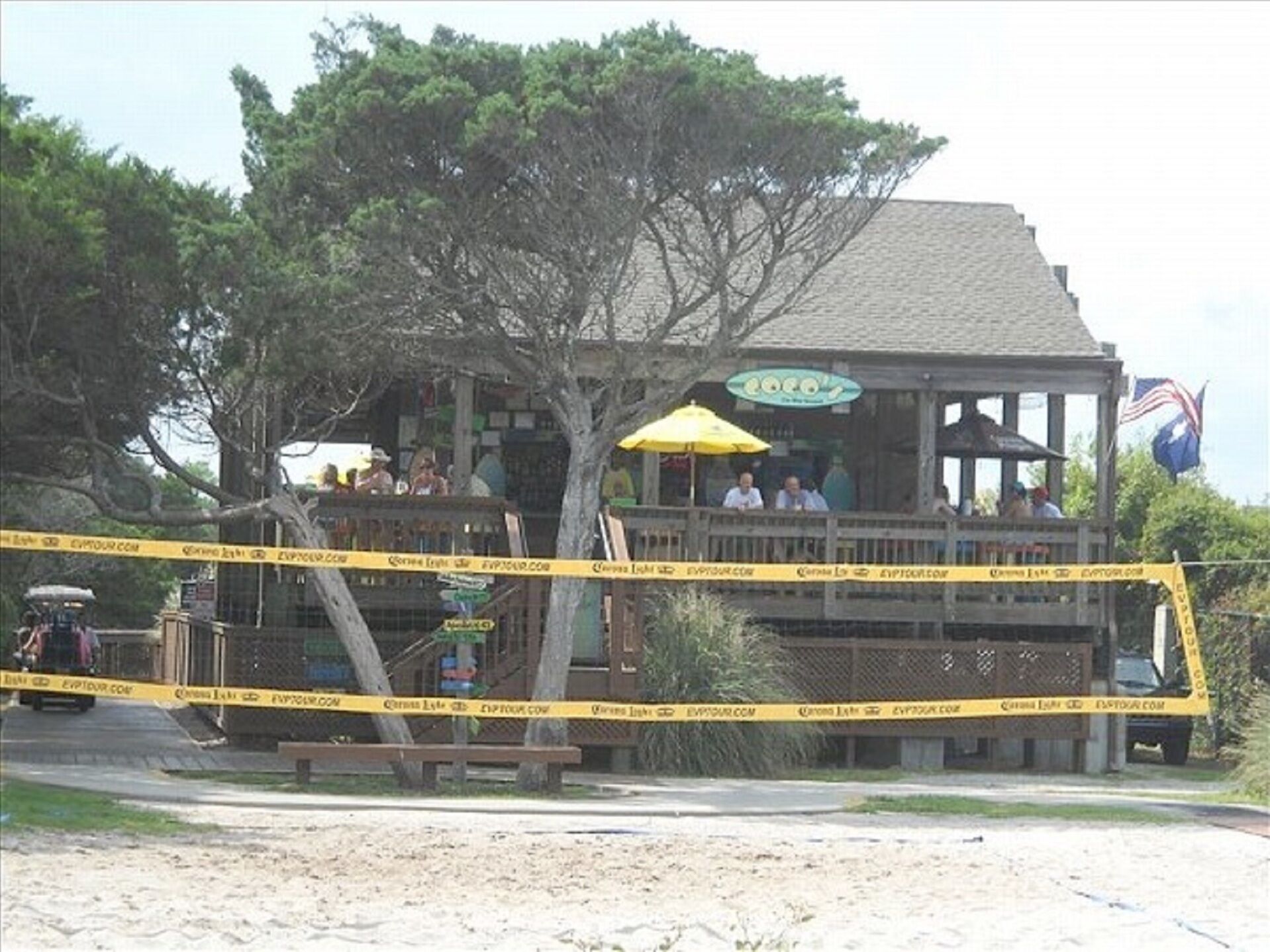 A wooden building with a balcony, surrounded by yellow caution tape.