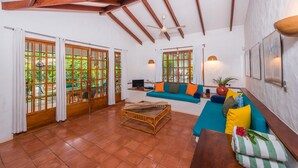 A spacious living room with a wooden ceiling, large windows, a sofa set, and a coffee table.