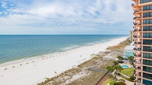 A beach view with a hotel building, clear skies, and a sandy shoreline.