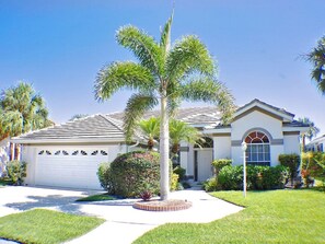 A residential house with a garage, a driveway, and a well-maintained lawn.