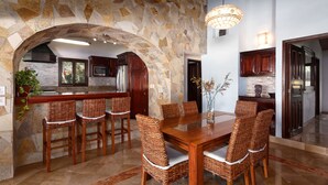 Un amplio comedor con un arco de piedra, muebles de madera y una cocina moderna al fondo.