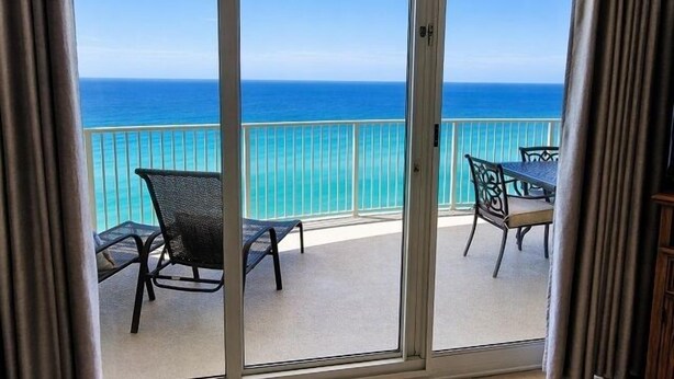 Uma varanda com vista para o oceano, uma mesa e duas cadeiras.