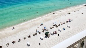 Uma praia com pessoas, guarda-sóis e cadeiras de praia.