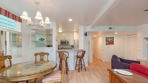 A dining area with a glass table, wooden chairs, and a chandelier. - Charming  2 Bedroom/2 Bath with Fireplace, Beach is 2 min Walk (San Diego)