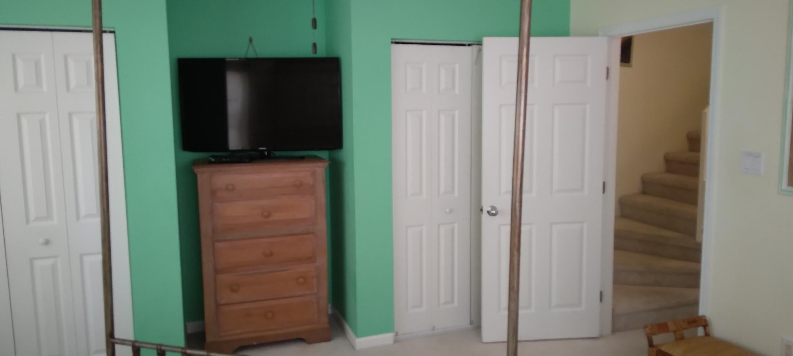 Ein Zimmer mit einem hölzernen Schminktisch, einem Fernseher darauf und zwei weißen Türen.
