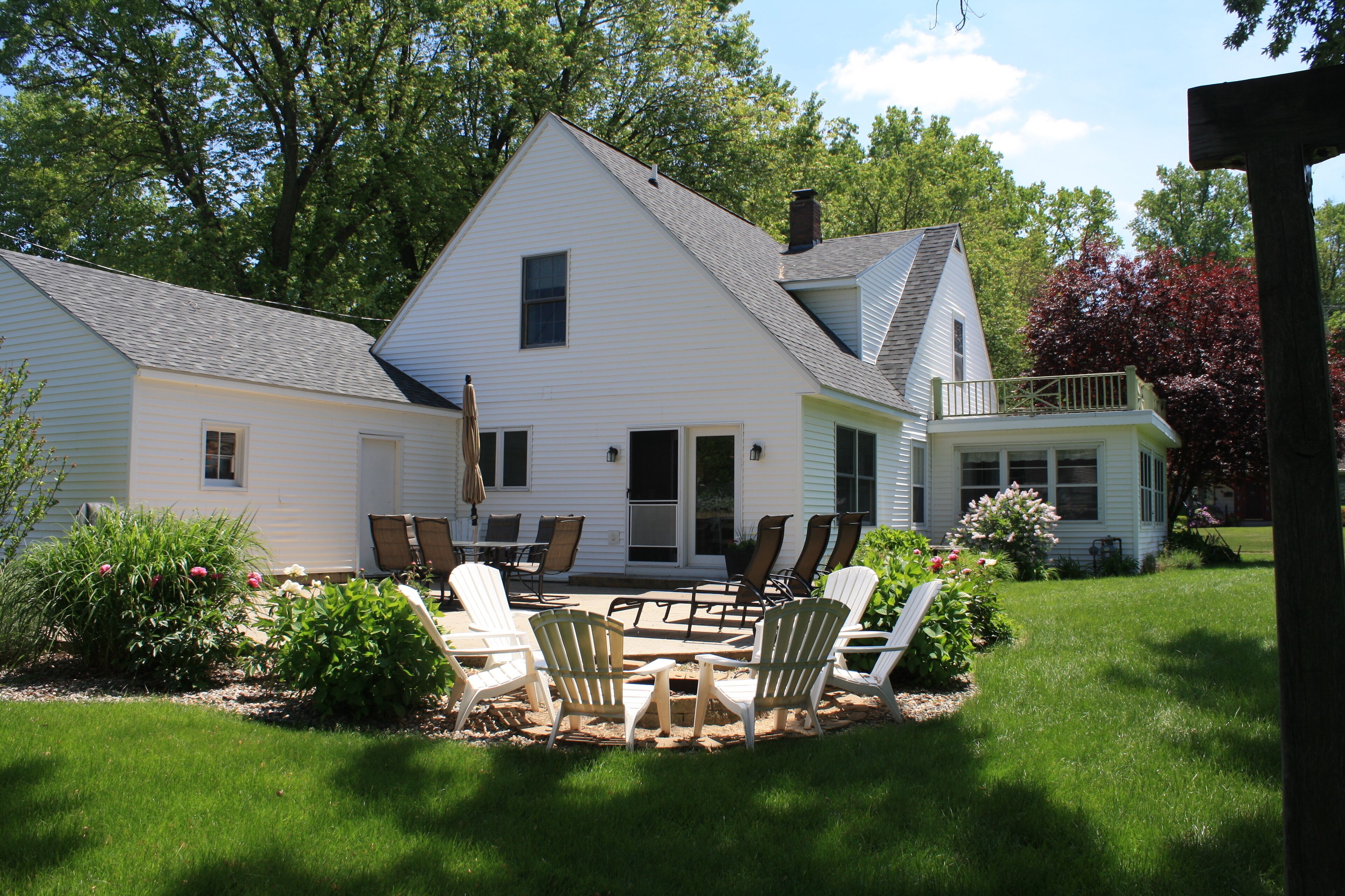 A two-story house with a patio area featuring outdoor furniture.