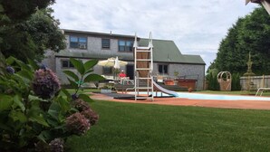 Patio trasero residencial con un tobogán, una escalera y una piscina.