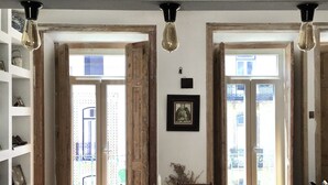 Une pièce avec une table en verre, des chaises en bois, une bibliothèque et deux portes ouvertes donnant sur un balcon extérieur.