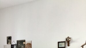 Une chambre à coucher avec un lit, un plancher en bois, une table de chevet, une lampe et des œuvres d’art murales.