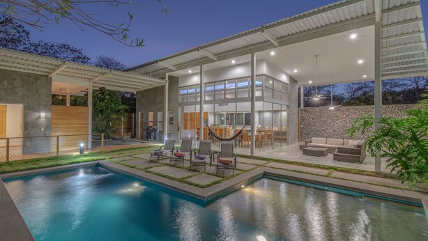A modern outdoor pool area with a dining area and seating. - Spacious Modern Home w/pool in gated community (Playa Guiones)