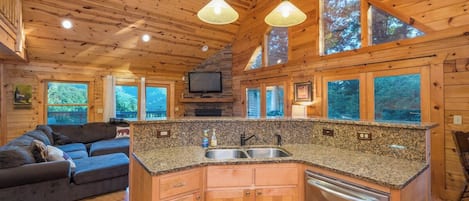 Een interieur van een chalet met een keukeneiland, houten plafond en een bank.