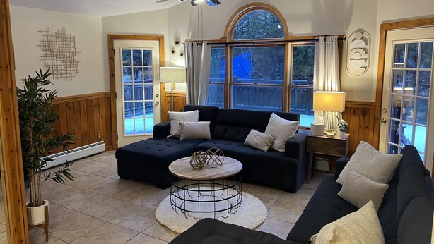 Ein gemütliches Wohnzimmer mit einem dunkelblauen Sofa, einem runden Couchtisch und einem Deckenventilator.