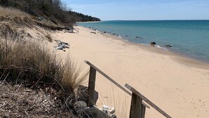 A sandy beach with a wooden fence and rocky outcrops.