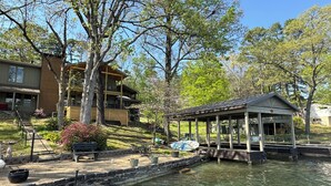 A riverside property with a wooden building, a covered pavilion, and a stone walkway leading to the water.