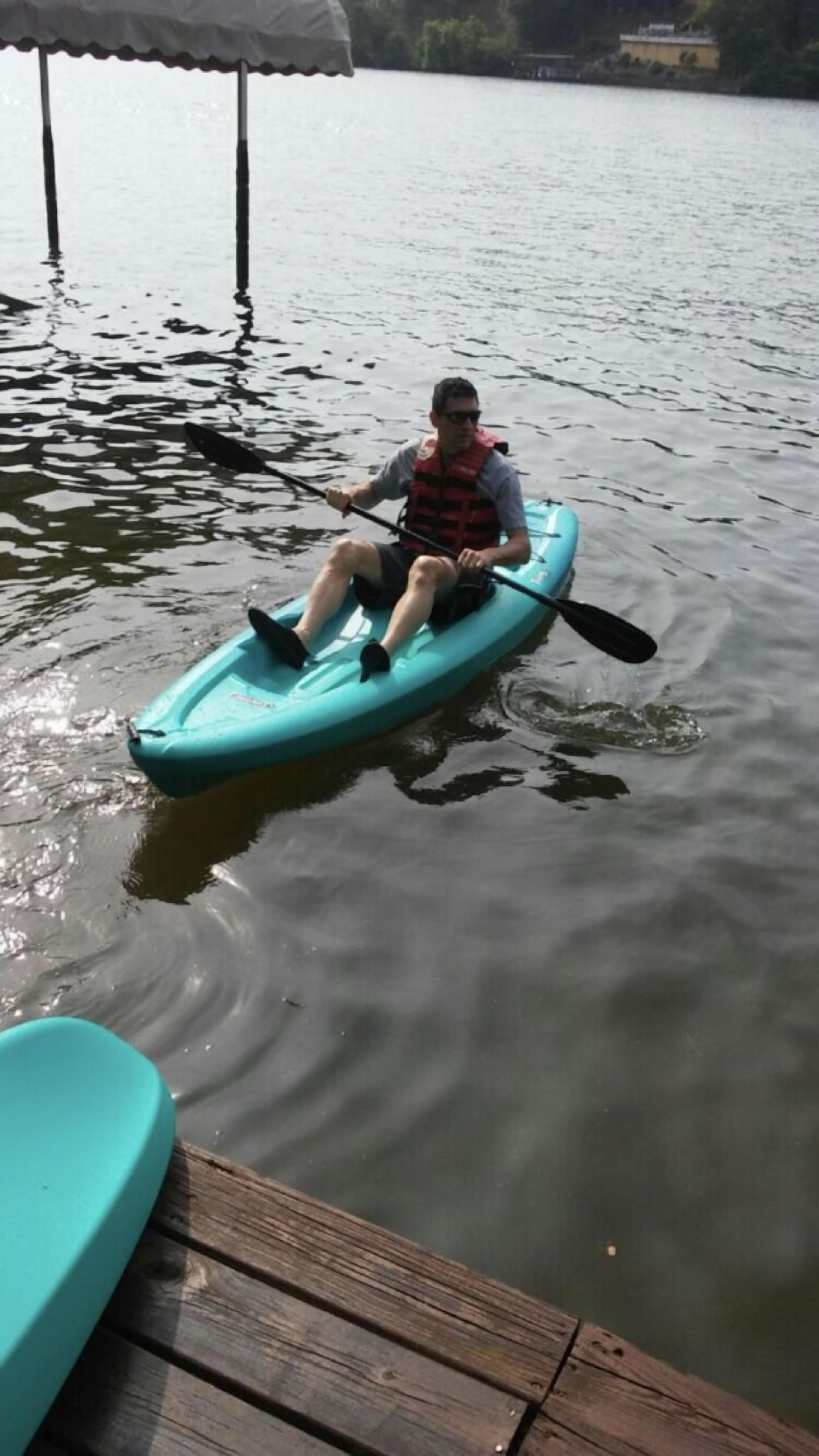 Eine Person paddelt mit einem Kajak auf einem ruhigen See.