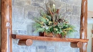 A stone fireplace with a wooden mantel, a decorative plant, and a black pot.