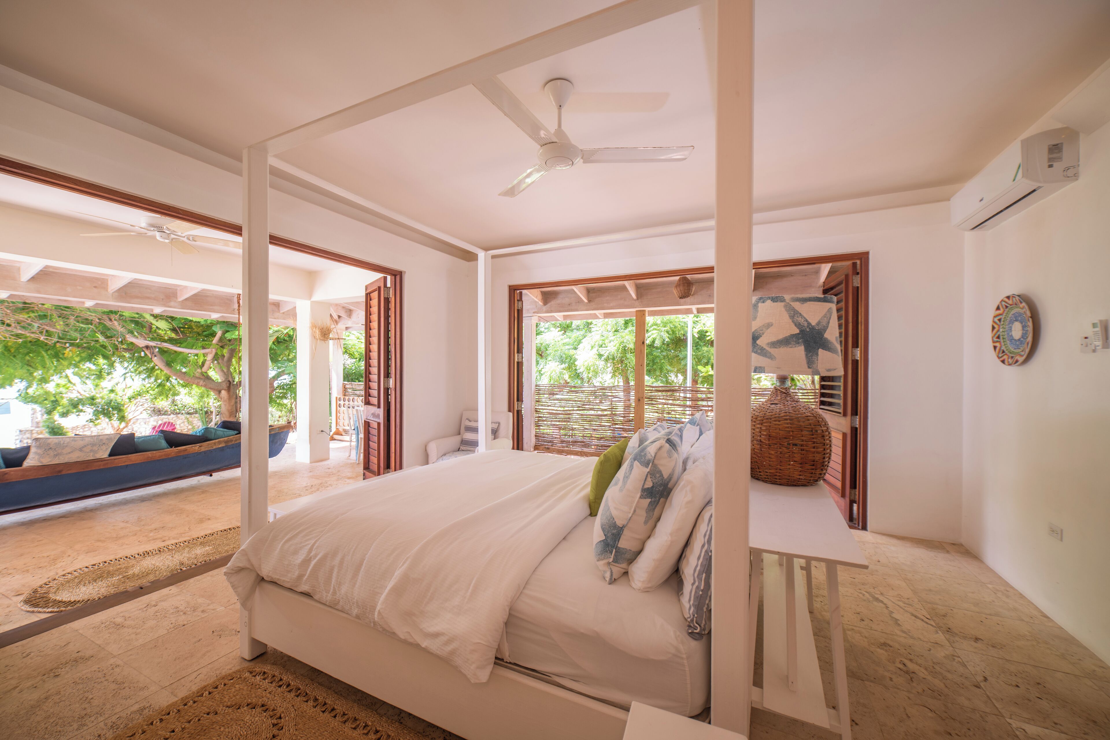 Une chambre à coucher avec un lit à baldaquin, un ventilateur de plafond et une vue sur l’extérieur.