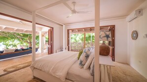 Ein Schlafzimmer mit Himmelbett, Deckenventilator und Blick ins Freie.