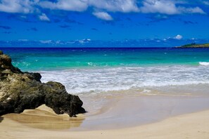 A beach with clear turquoise water, a sandy shore, and a rocky outcrop. - Gorgeous Oceanfront! - Sweeping Views & Steps to the Beach (Lahaina)