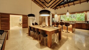 A spacious kitchen with a large wooden table, modern chairs, and pendant lights.