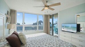 A bedroom with a large bed, a ceiling fan, a television, and a view of the ocean through the windows. - JUST RENOVATED! Amazing Views!!! Beautiful Updated 2 Bedroom, 2 Bath condo! (Miramar Beach)
