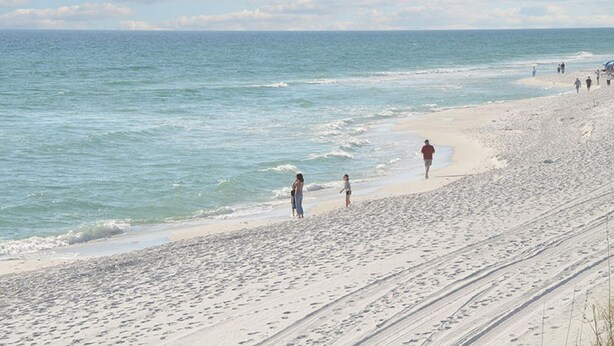 Una playa con gente caminando por la orilla.