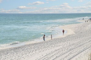 A beach with people walking along the shore.